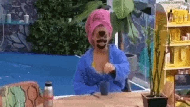 a woman with a towel wrapped around her head is sitting at a table .