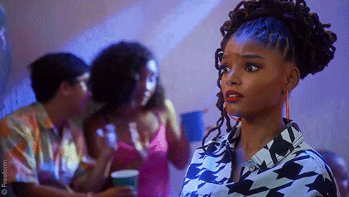 a woman with dreadlocks is standing in front of a group of people in a room .