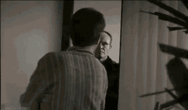 a man is standing in front of a mirror looking at himself .