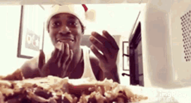 a man wearing a santa hat is looking into a microwave oven .