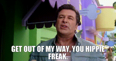 a man is standing in front of a colorful building and says `` get out of my way , you hippie freak ''