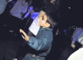 a young boy wearing sunglasses and a mask is dancing in a club .