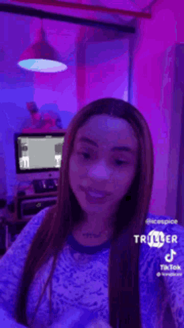 a woman is standing in a room with purple lights and a computer .