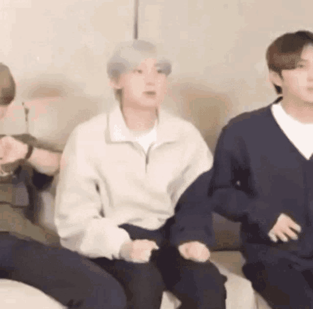 a group of young men are sitting on a couch in a living room .