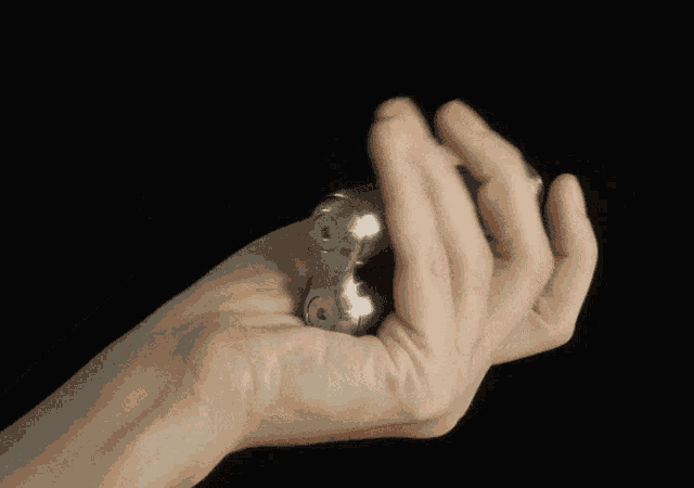 a close up of a person 's hand holding a small metal object