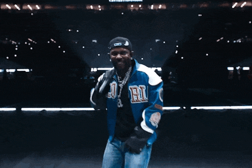 a man in a blue jacket is dancing on a tennis court while holding a microphone ..