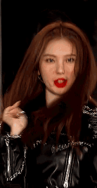 a close up of a woman wearing a black leather jacket and red lipstick