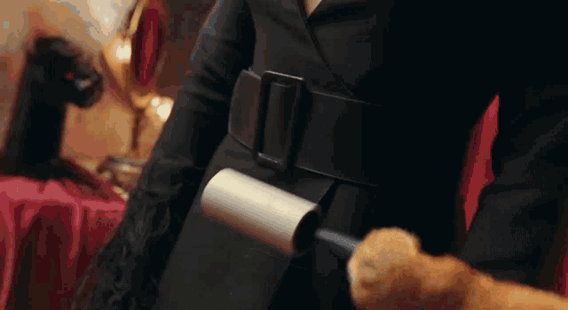 a woman in a black coat holds a roll of toilet paper