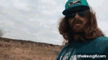 a man with long hair and a beard wearing sunglasses and a hat with the word billabong on it