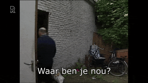 a man standing in front of a brick wall with the words waar ben je nou written on the bottom