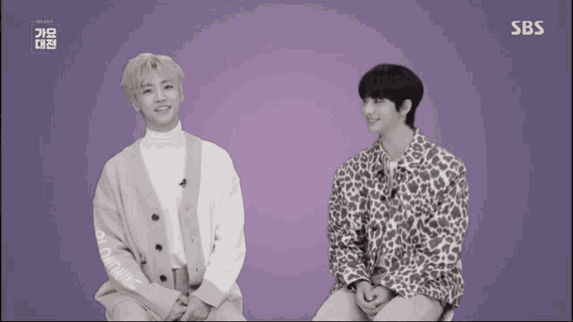 two men are sitting next to each other with sbs written in the corner