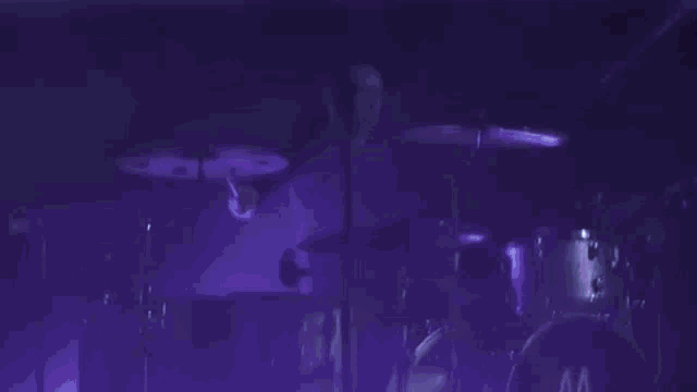 a drummer is playing a drum set in a dark room