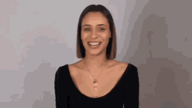 a woman wearing a necklace and a black shirt is smiling .