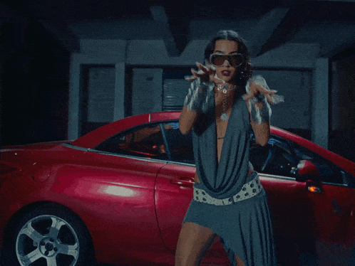 a woman wearing sunglasses stands in front of a red car that has the word sxsxs on the windshield