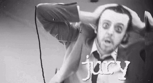 a man in a suit and tie is singing into a microphone with the word juicy written on the bottom