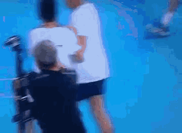 a blurry picture of a man in a white shirt standing on a blue surface