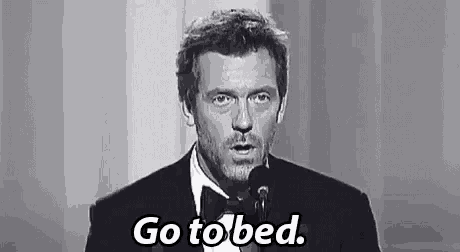 a man in a suit and bow tie is standing in front of a microphone and saying `` go to bed . ''