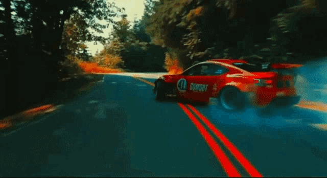 a red car with the number 11 on it is drifting down a road