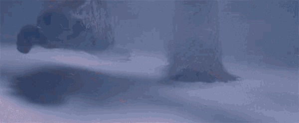 a cartoon yeti with horns is standing in the snow and giving a thumbs up .
