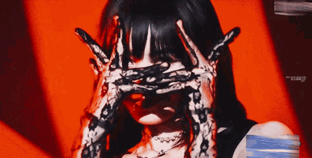 a woman with black gloves on her hands is covering her eyes .