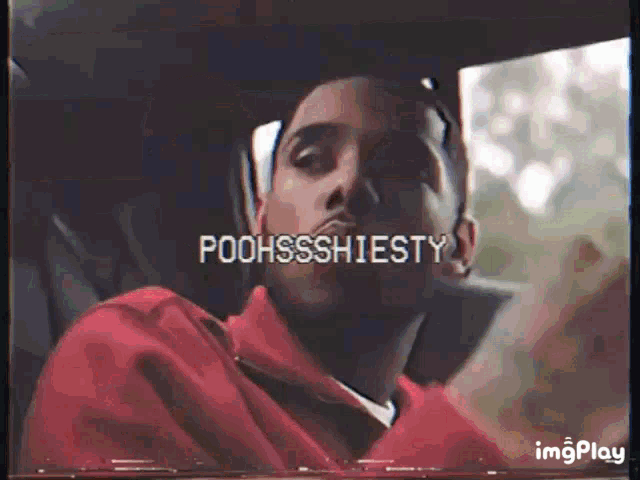 a man in a red jacket is sitting in a car with the words poohssshiesty on the screen