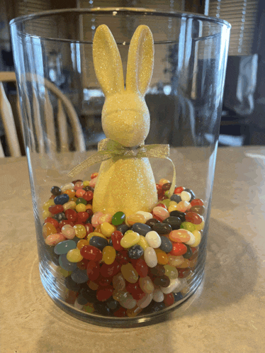 a glass filled with jelly beans and a yellow bunny on top