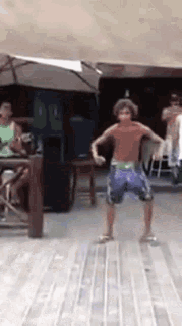 a boy in purple shorts is dancing on a deck .