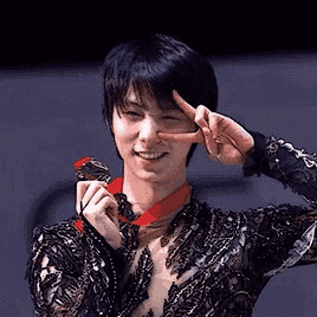 a man is holding a medal around his neck and giving a peace sign .