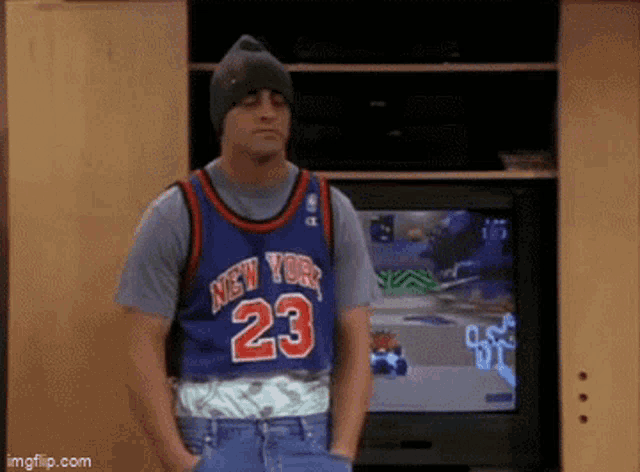a man wearing a new york jersey is standing in front of a tv .