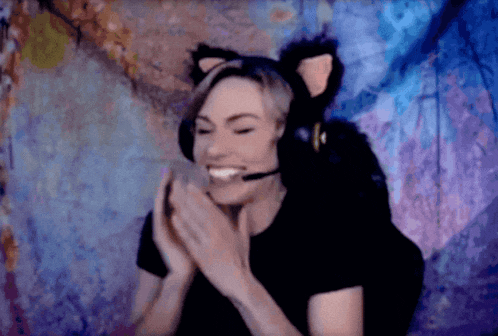 a woman wearing a cat ear headset is smiling and clapping