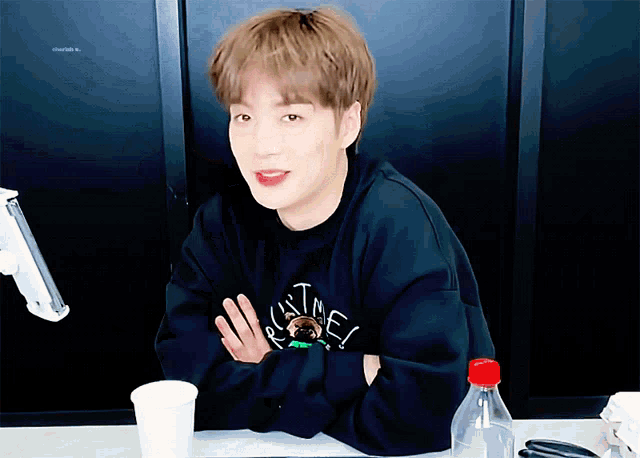 a young man wearing a sweatshirt that says ' ultimate ' on it sits at a table