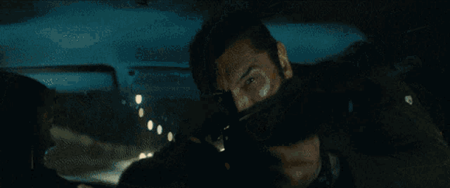 a man in a car is holding a gun and shooting it