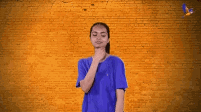 a woman in a blue shirt is standing in front of a brick wall with the word integrity on it