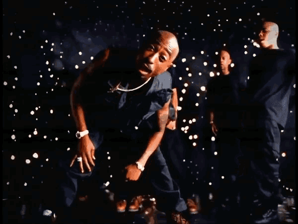 a group of men are dancing in a dark room with a man wearing a watch on his wrist