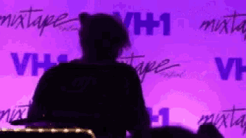 a man is standing in front of a purple wall that says vh1 on it