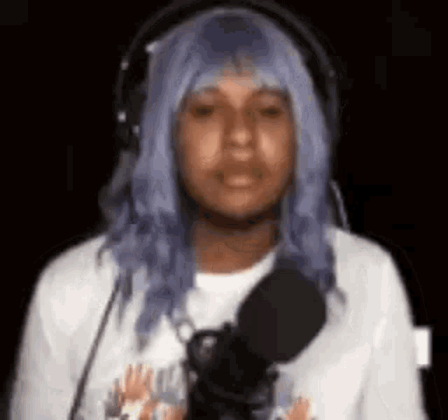 a man with purple hair is wearing headphones and a microphone .