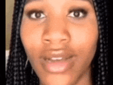 a close up of a woman 's face with braids and a smile on her face .