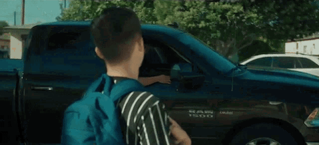 a man with a backpack is standing next to a ram truck