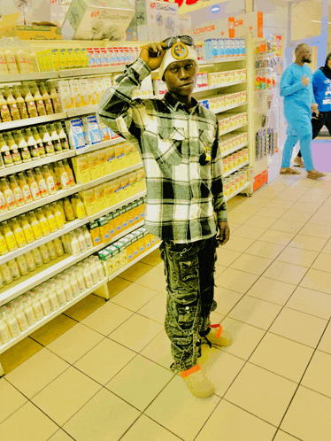 a man in a plaid shirt is standing in a grocery store with a sign that says ' sonic ' on it