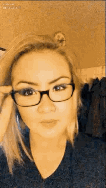 a woman wearing glasses is taking a selfie with her phone .