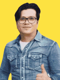 a man wearing glasses and a blue denim shirt gives a thumbs up
