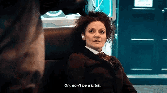 a woman with curly hair is sitting in a chair and talking to a man .
