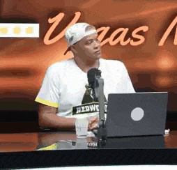 a man is sitting at a table with a laptop and a microphone in front of him .