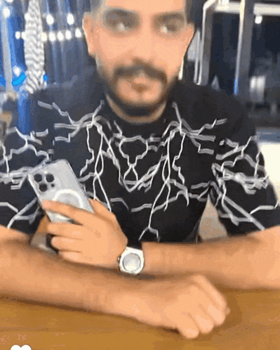 a man wearing a watch holds a cell phone in his hand