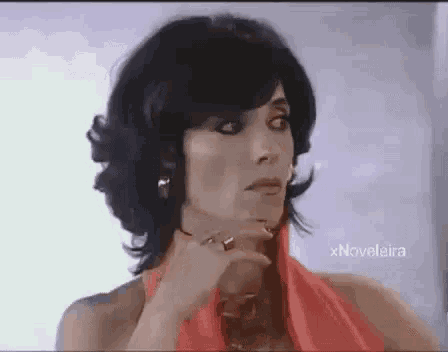 a woman in a red dress is making a funny face while holding her hand to her chin .