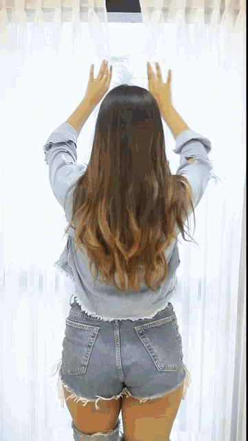 a woman in shorts is standing in front of a window
