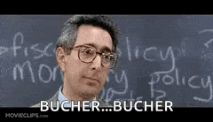 a man wearing glasses is standing in front of a blackboard with the words bucher written on it .