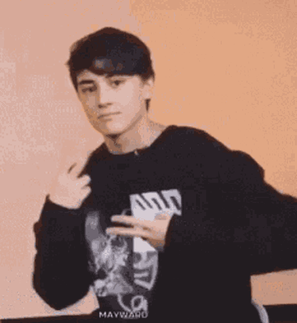 a young man in a black sweater is giving a peace sign .