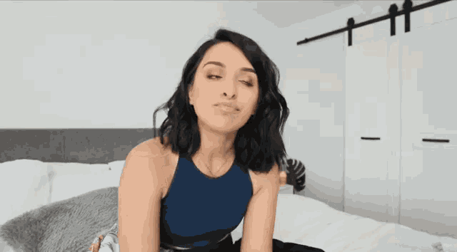 a woman sitting on a bed with her eyes closed