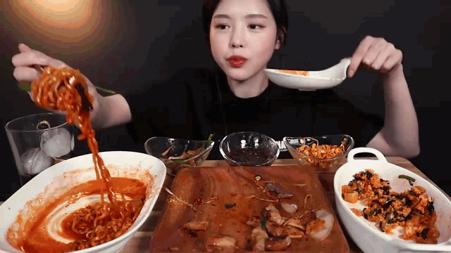 a woman is sitting at a table with bowls of food